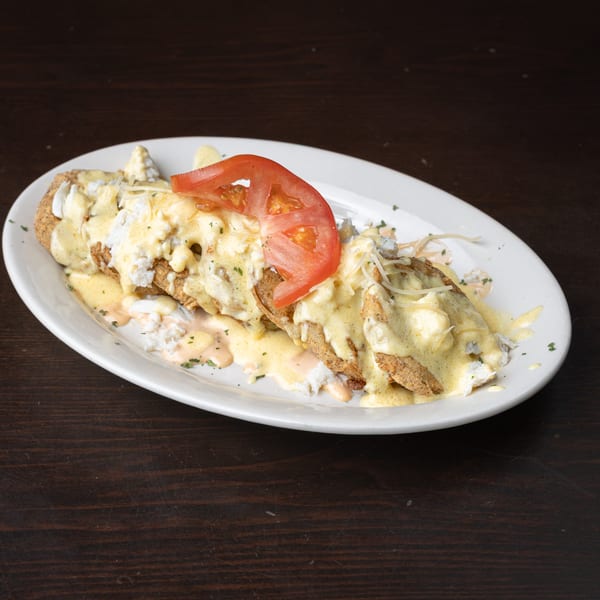 Fried seafood dish topped with creamy sauce, crab meat, cheese, and a tomato slice.